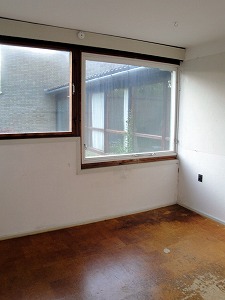 カーテンが外された部屋とすり切れたコルクの床。